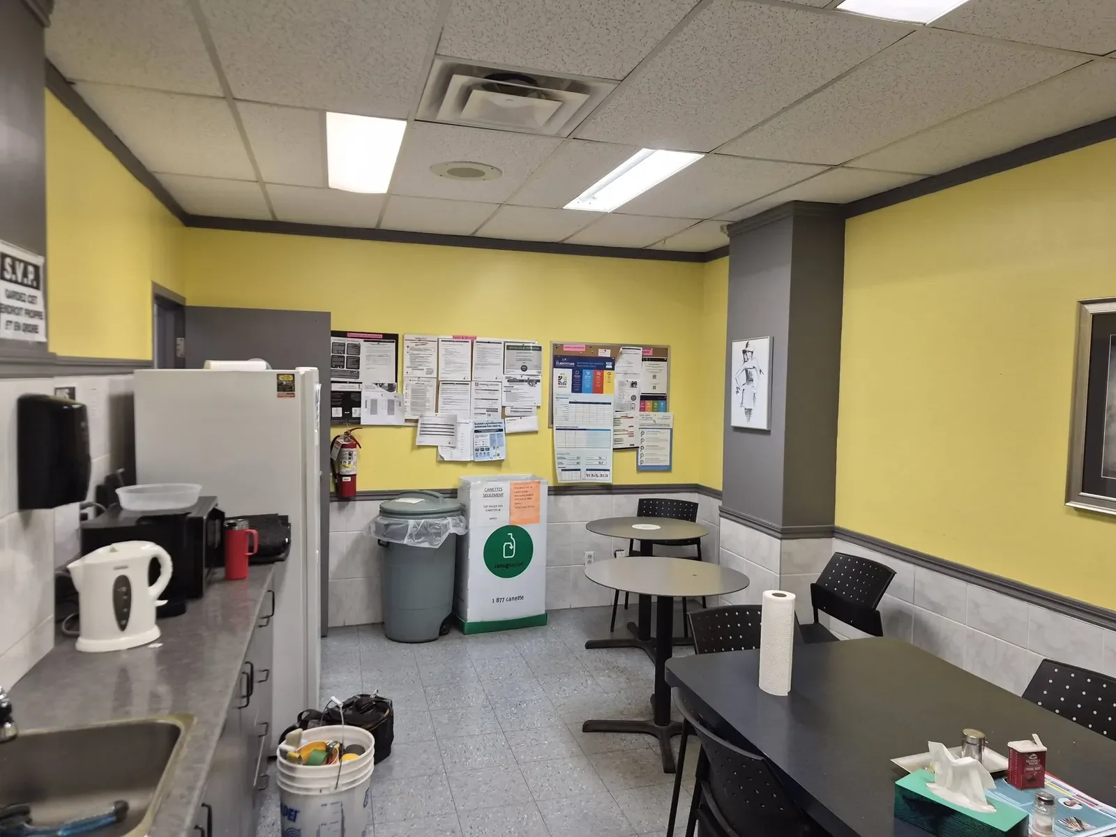 Salle des employés avec tables et babillard