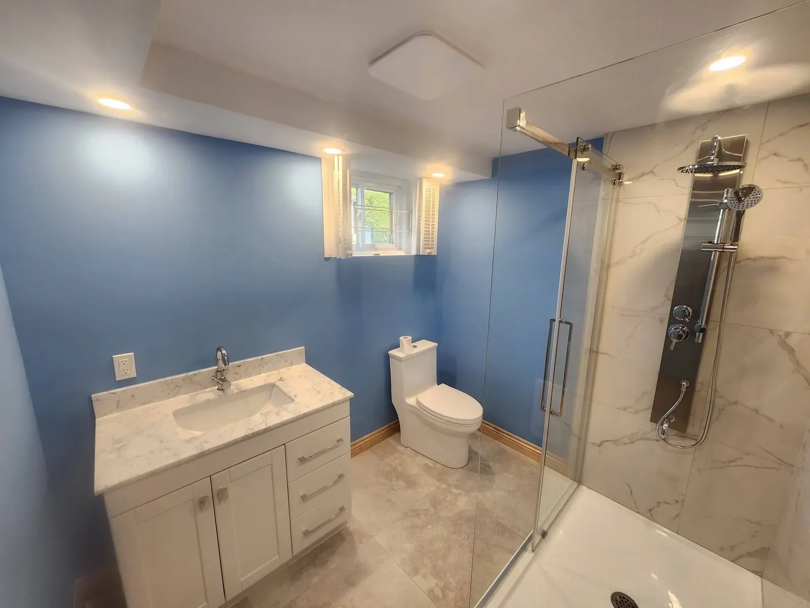 Salle de bain terminée avec douche vitrée, vanité et toilette